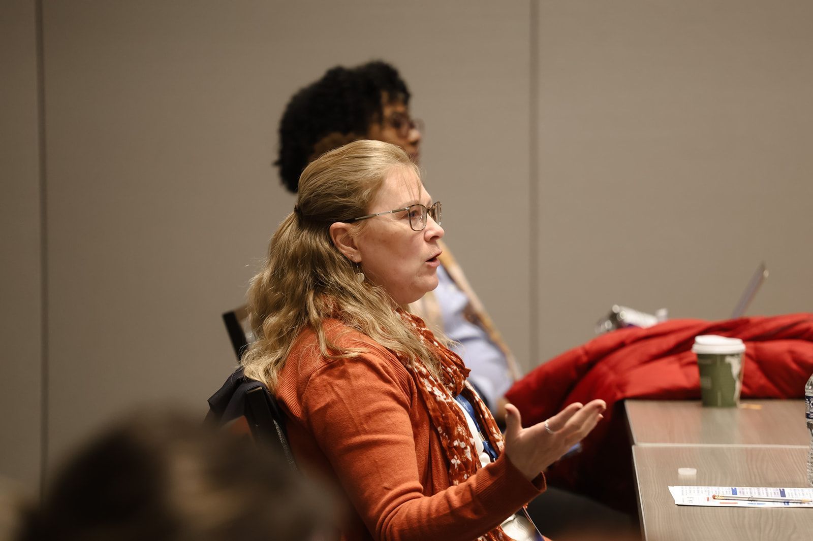 A woman is sitting at a table talking to a group of people.