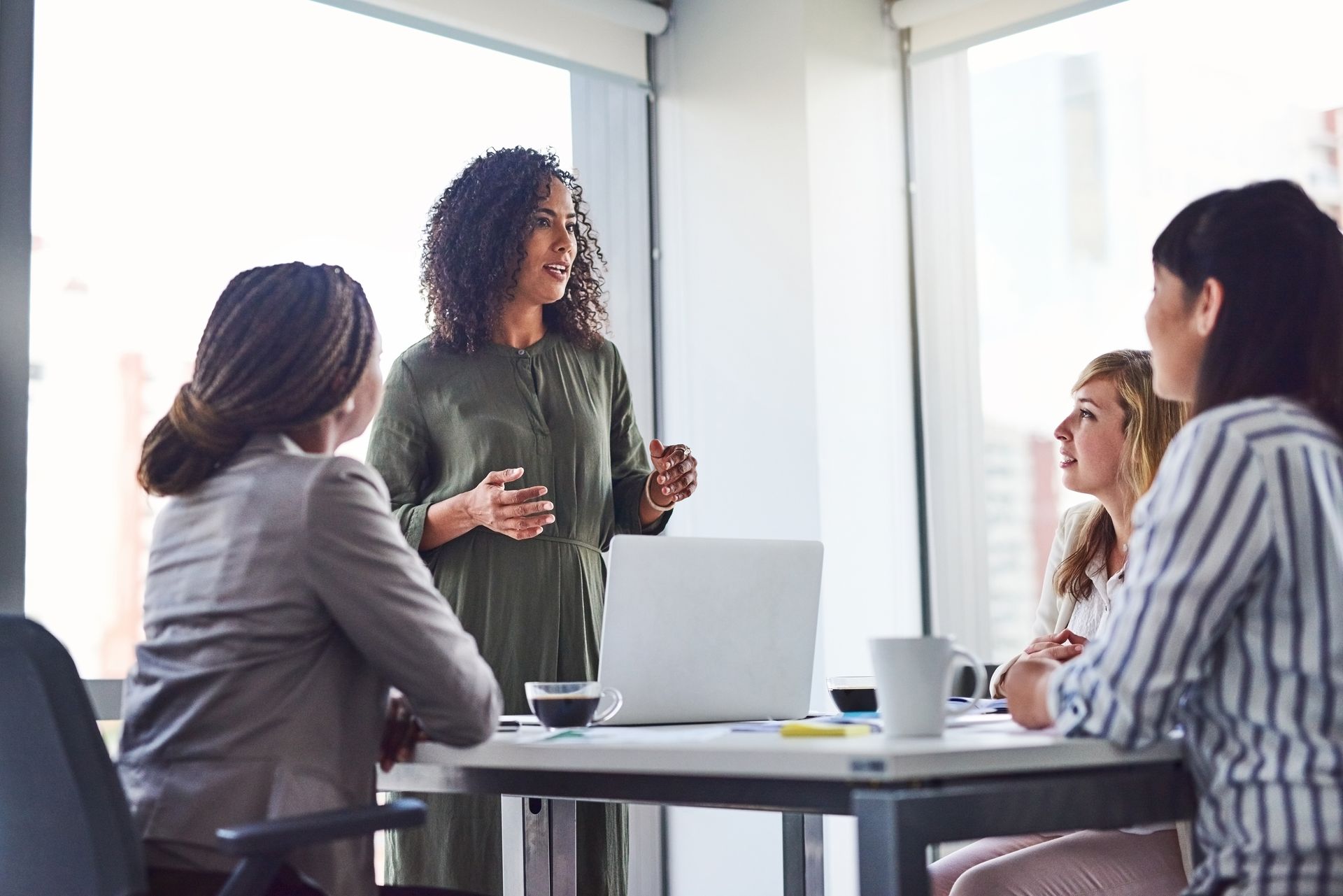 Woman leads a meeting in a modern office with colleagues seated at a table.