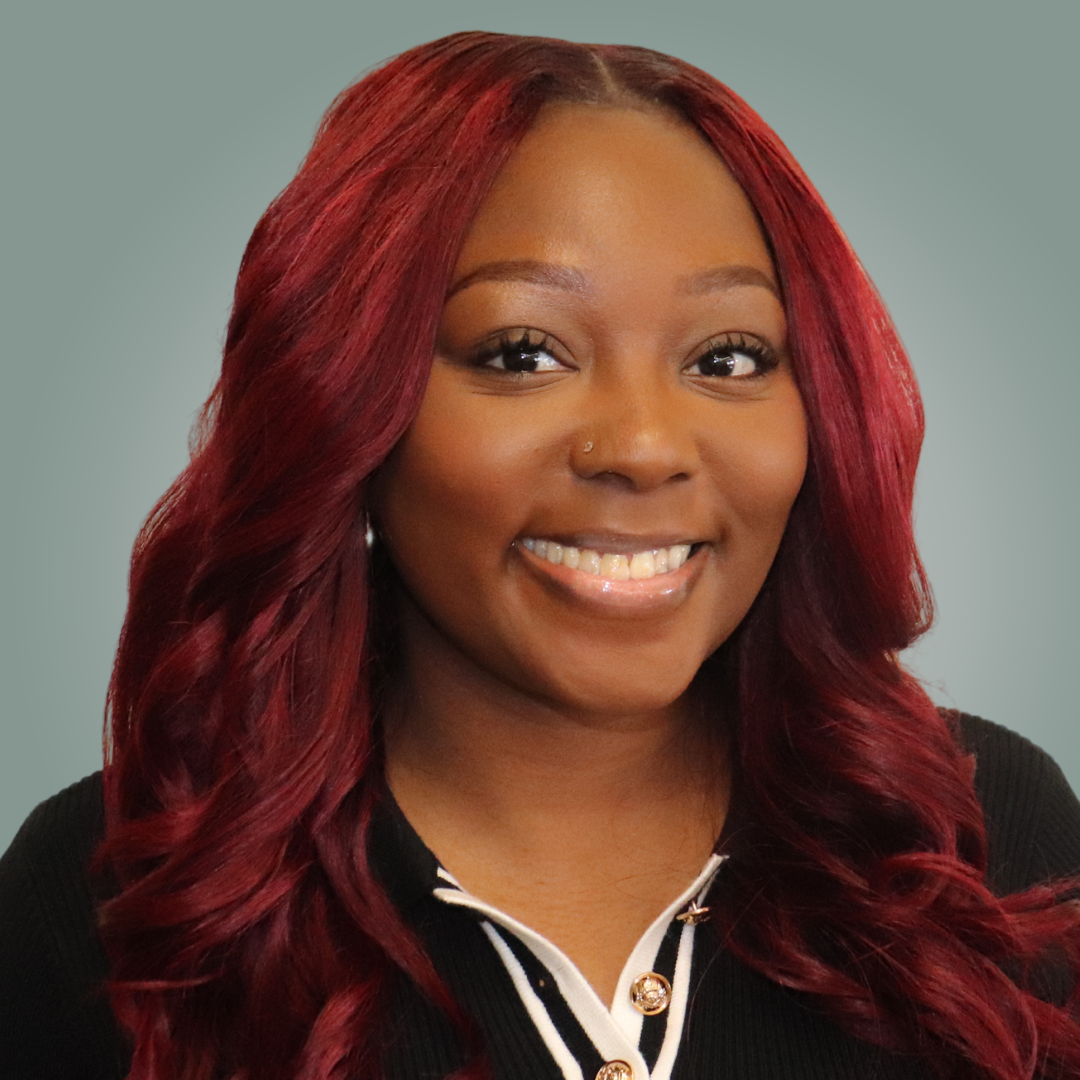 A woman with red hair is smiling for the camera