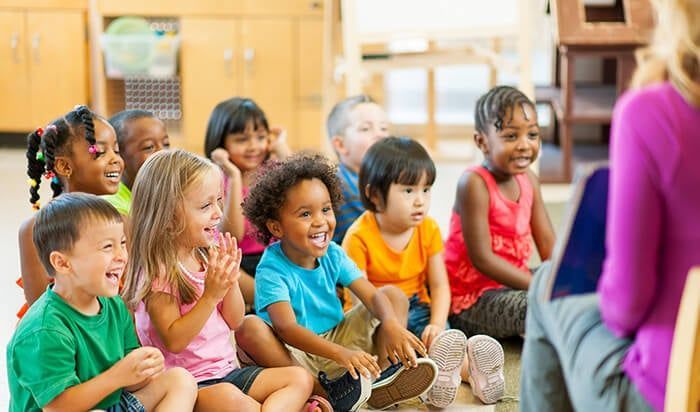 A group of children are sitting on the floor listening to a story.