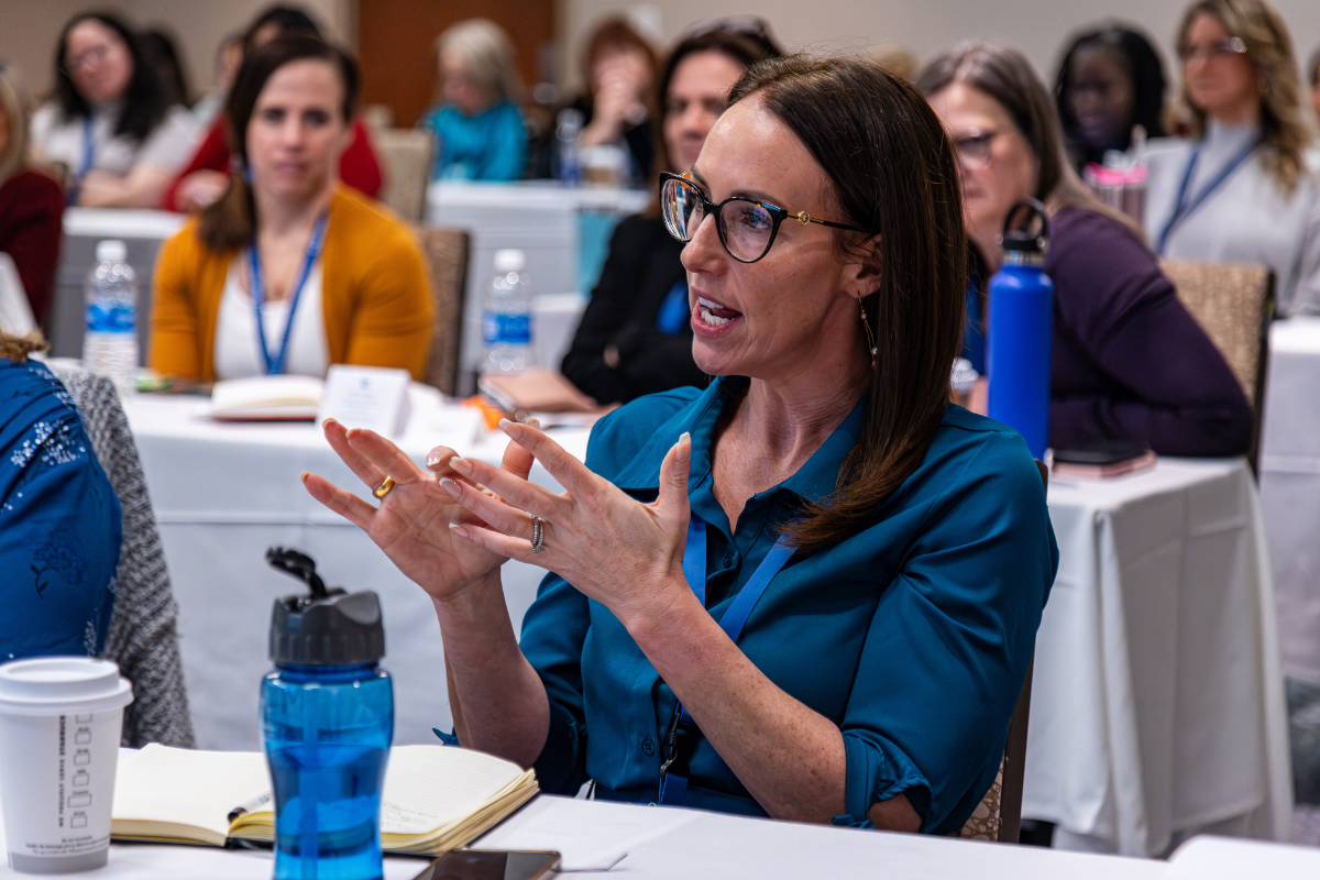 A woman is sitting at a table talking to a group of people.