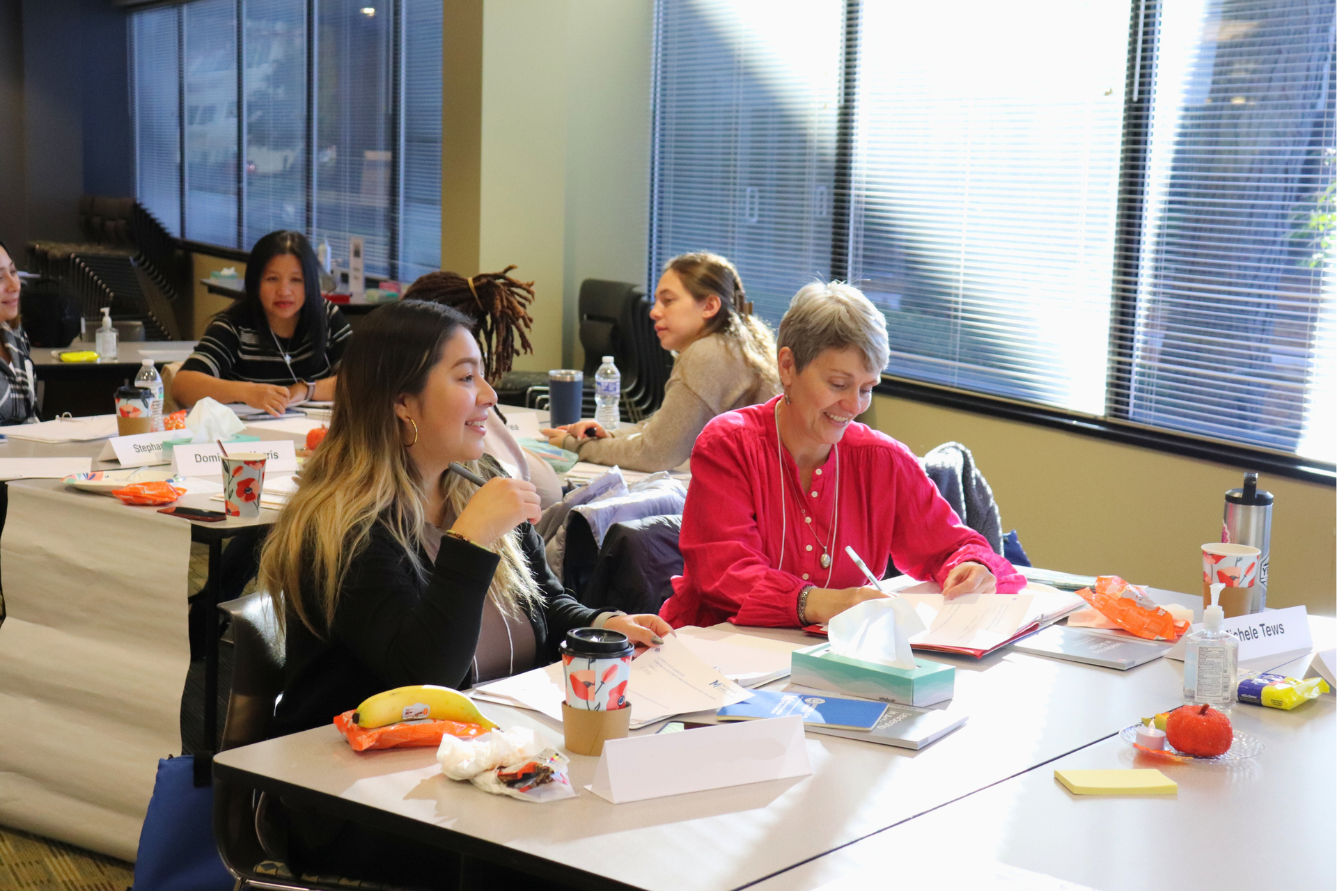 Group of people in a meeting; woman in front giving a presentation.