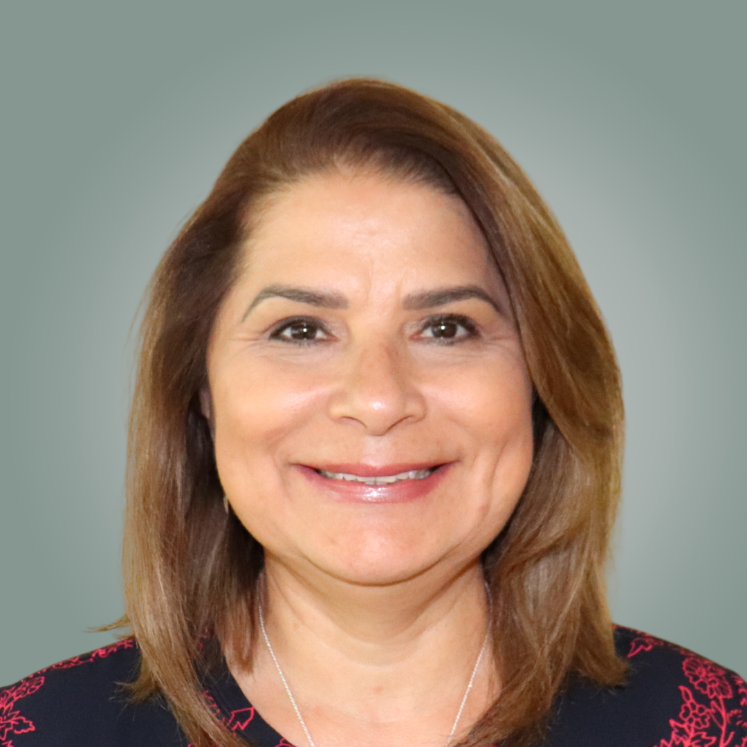 A woman with long brown hair and a white shirt is smiling for the camera.