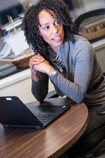 A woman is sitting at a table with a laptop on it.
