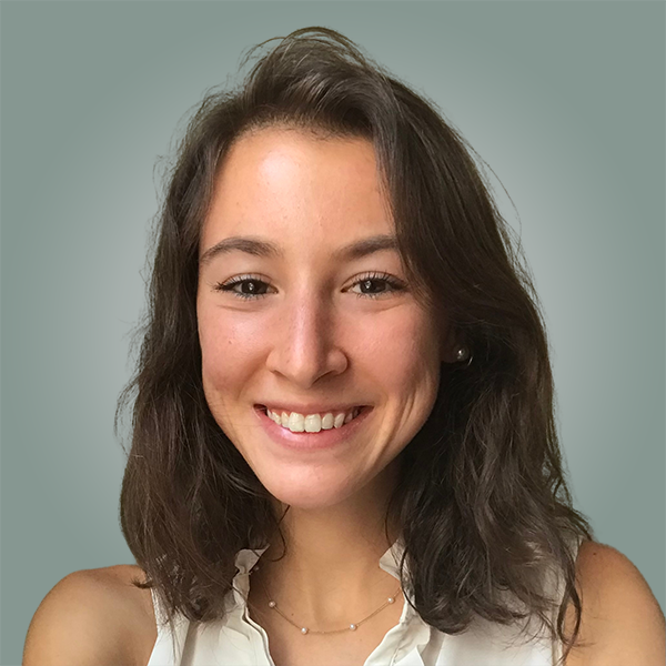 A woman with long brown hair and a white shirt is smiling for the camera.