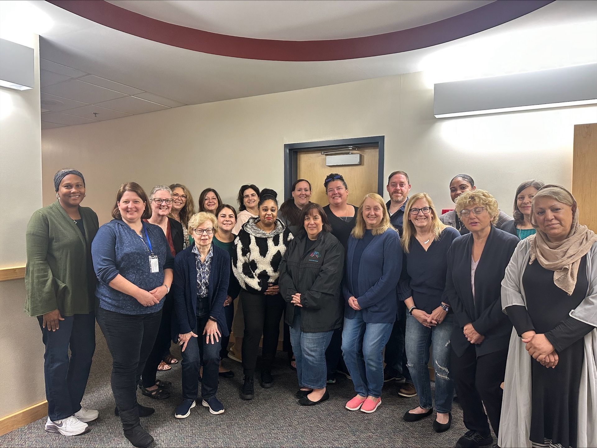 Group of people standing in a hallway, smiling at the camera.