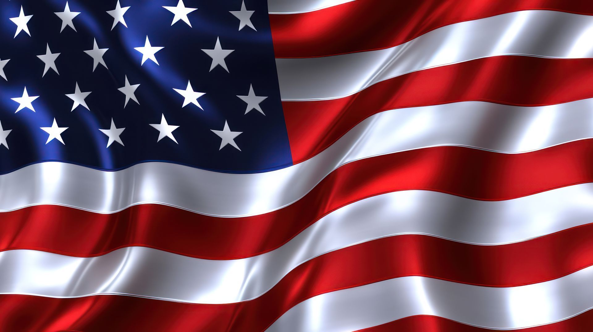 American flag waving in the wind, red and white stripes with a blue canton of white stars.