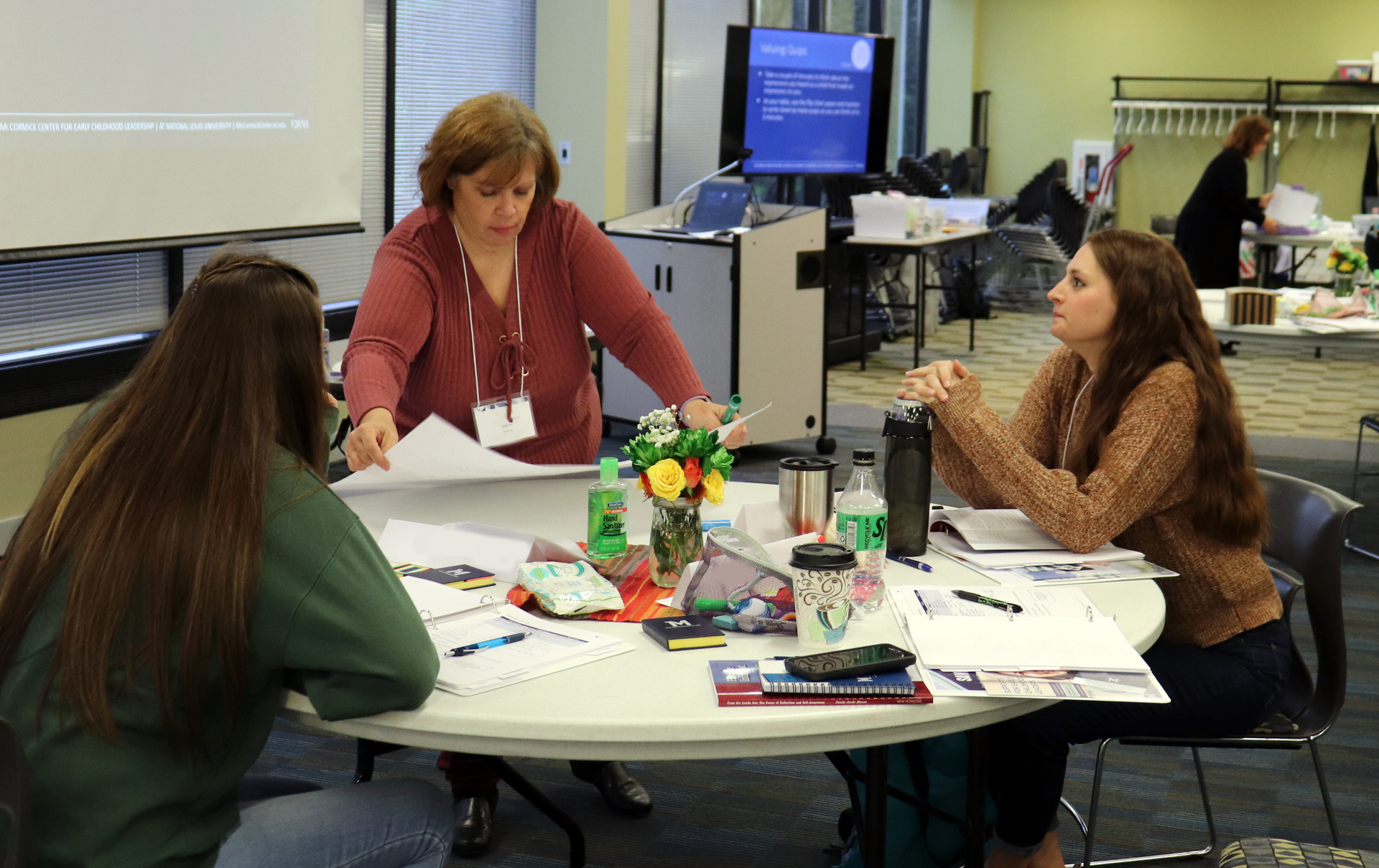 A group of women are sitting around a table in a room.