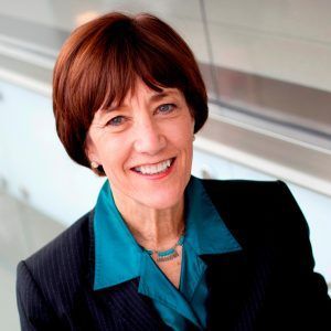 A woman in a suit and blue shirt is smiling for the camera.