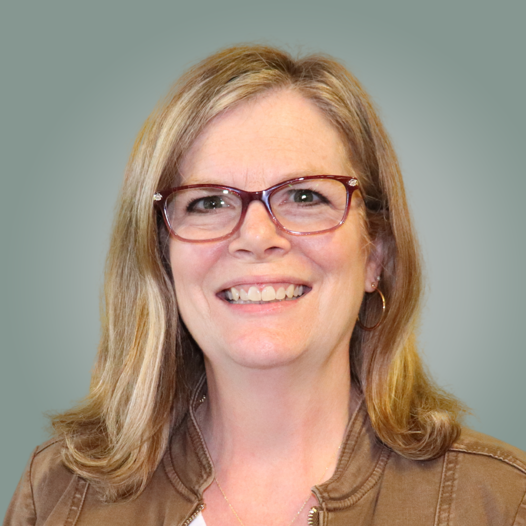 A woman in a purple shirt is smiling for the camera
