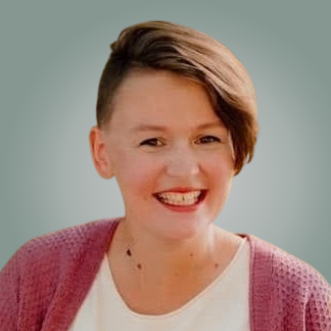 A woman wearing glasses and a green shirt is smiling for the camera.