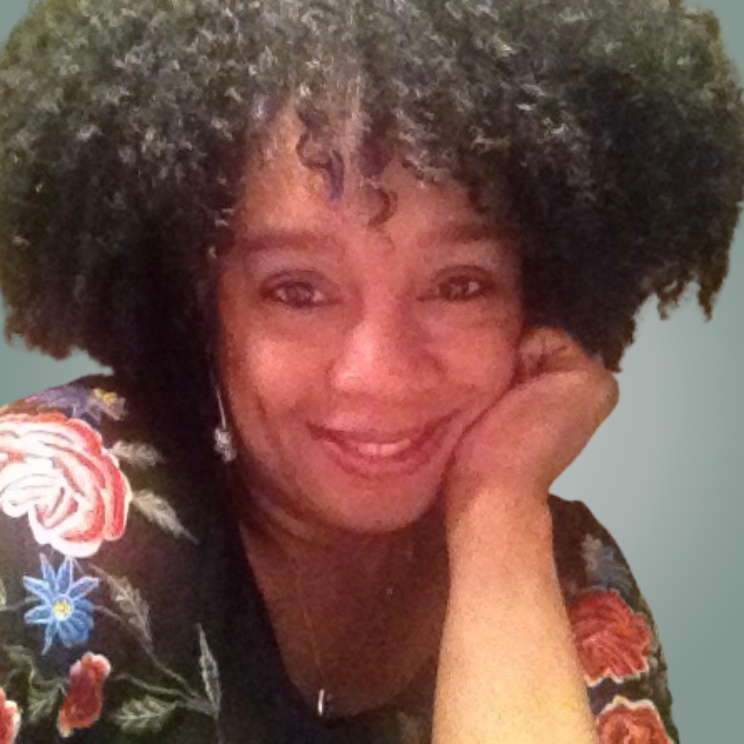 A woman with dreadlocks is smiling for the camera.