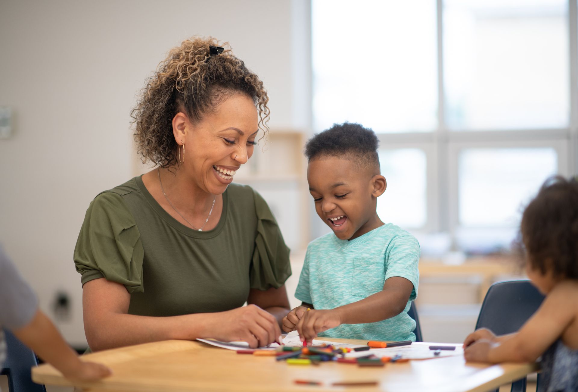 A woman is sitting at a table with a young boy.