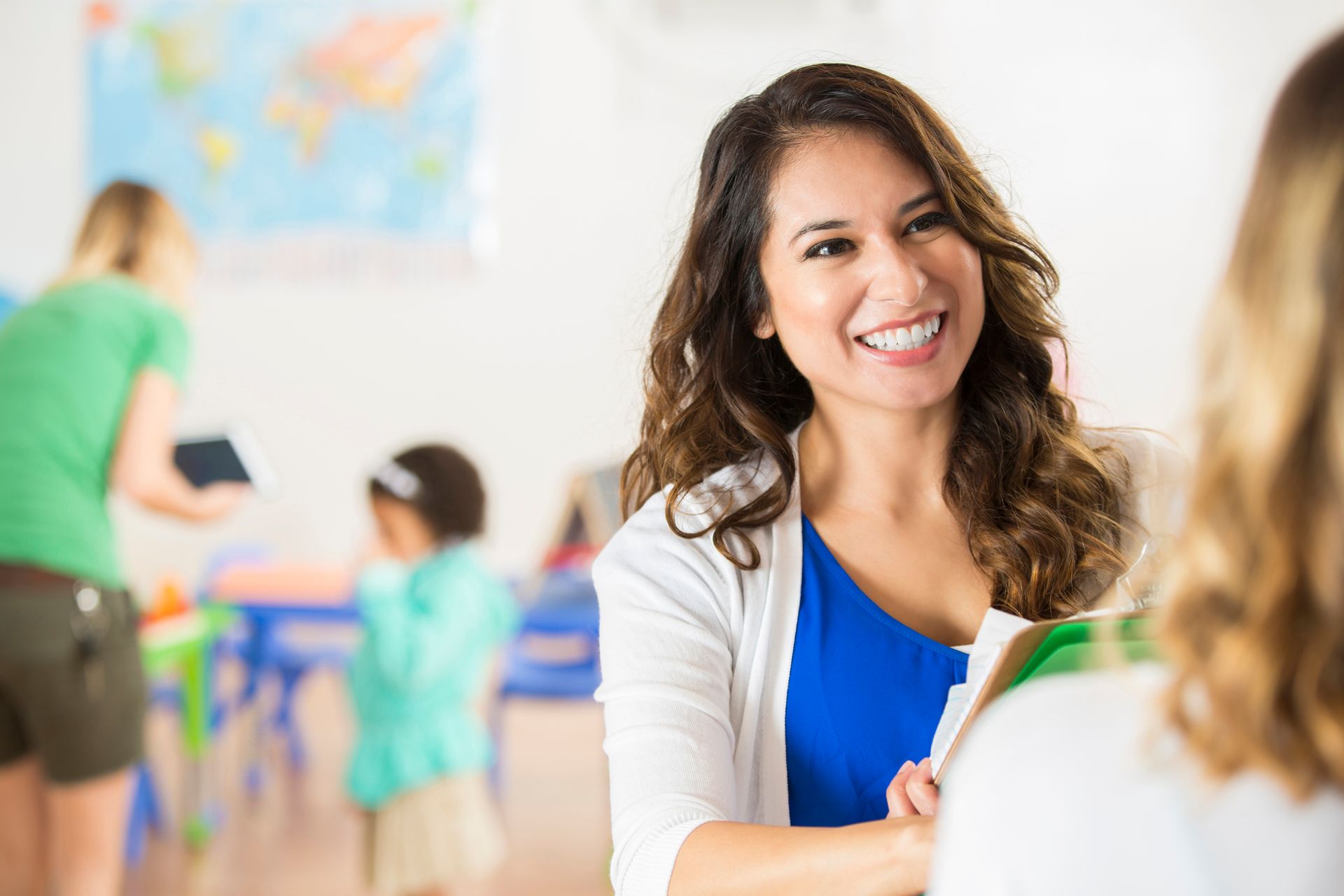 A woman is smiling while talking to another woman in a classroom.