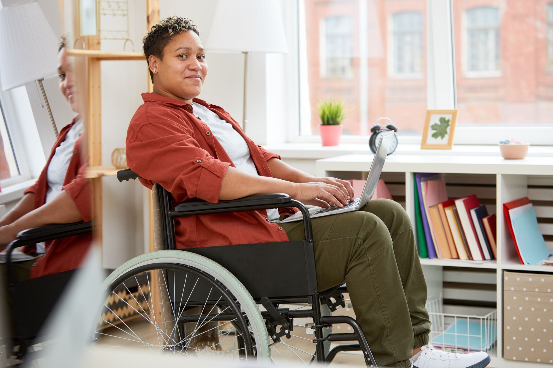 A woman in a wheelchair is using a laptop computer.