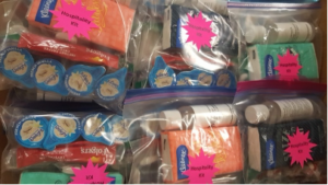 A bunch of plastic bags filled with toys are lined up on a table.