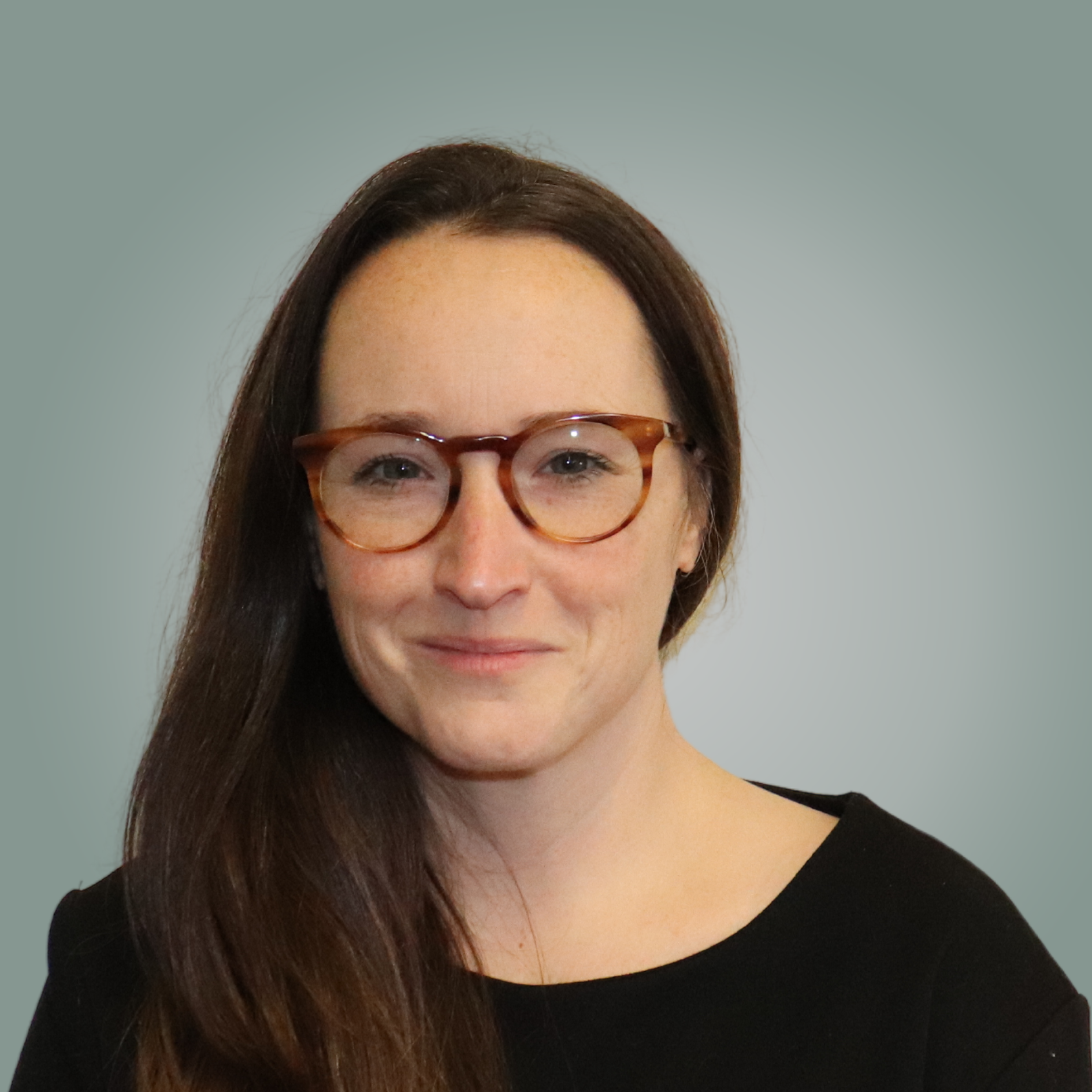 A woman wearing glasses and a black shirt is smiling for the camera.