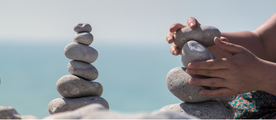 A person is stacking rocks on top of each other on a beach.