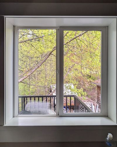 A window with a view of a balcony and trees.
