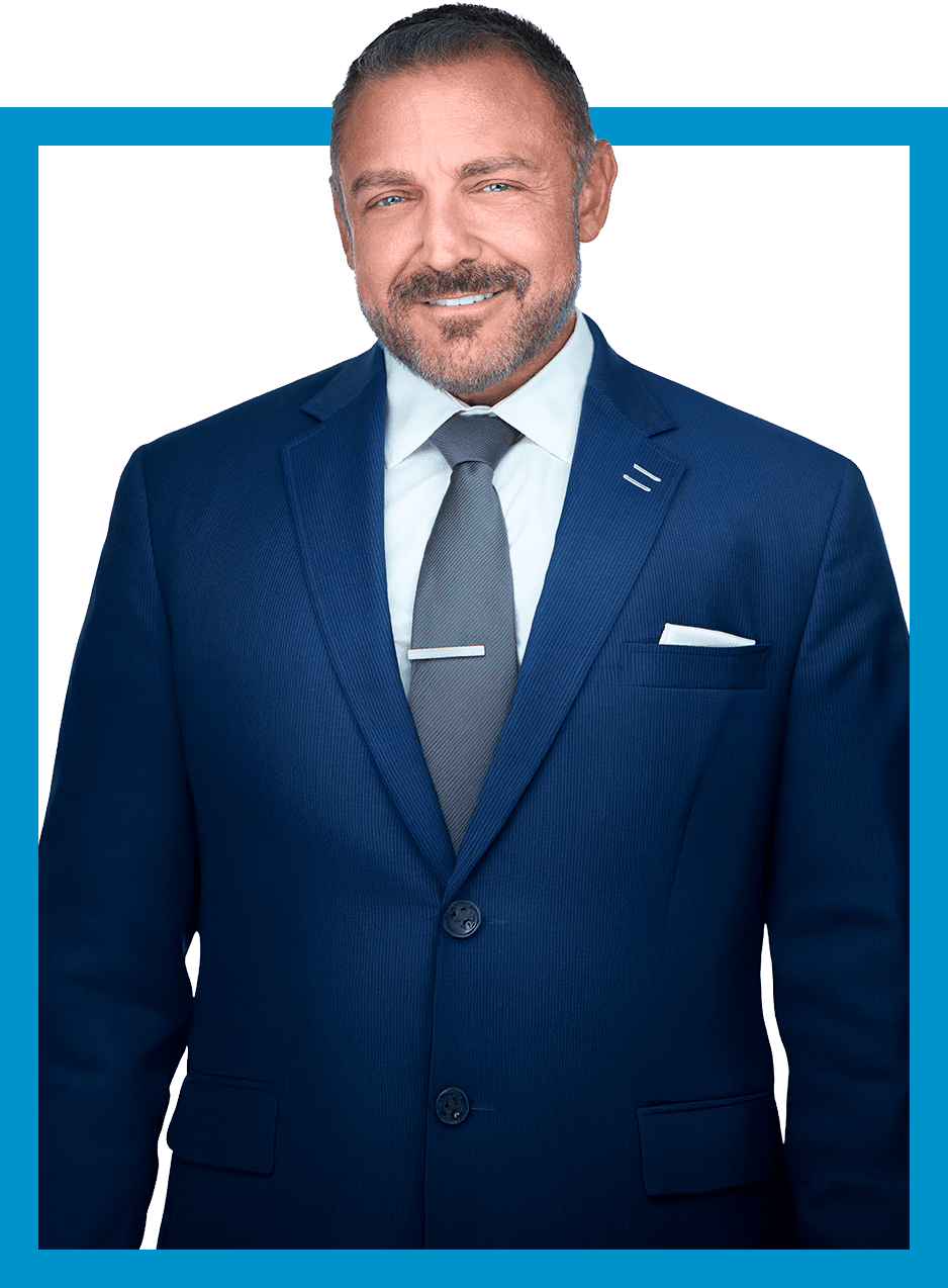 Man in a blue suit and tie, smiling, in a blue-bordered frame.
