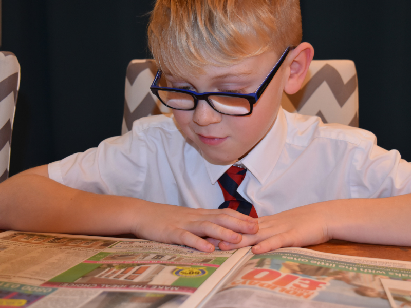 school child reading a newspaper