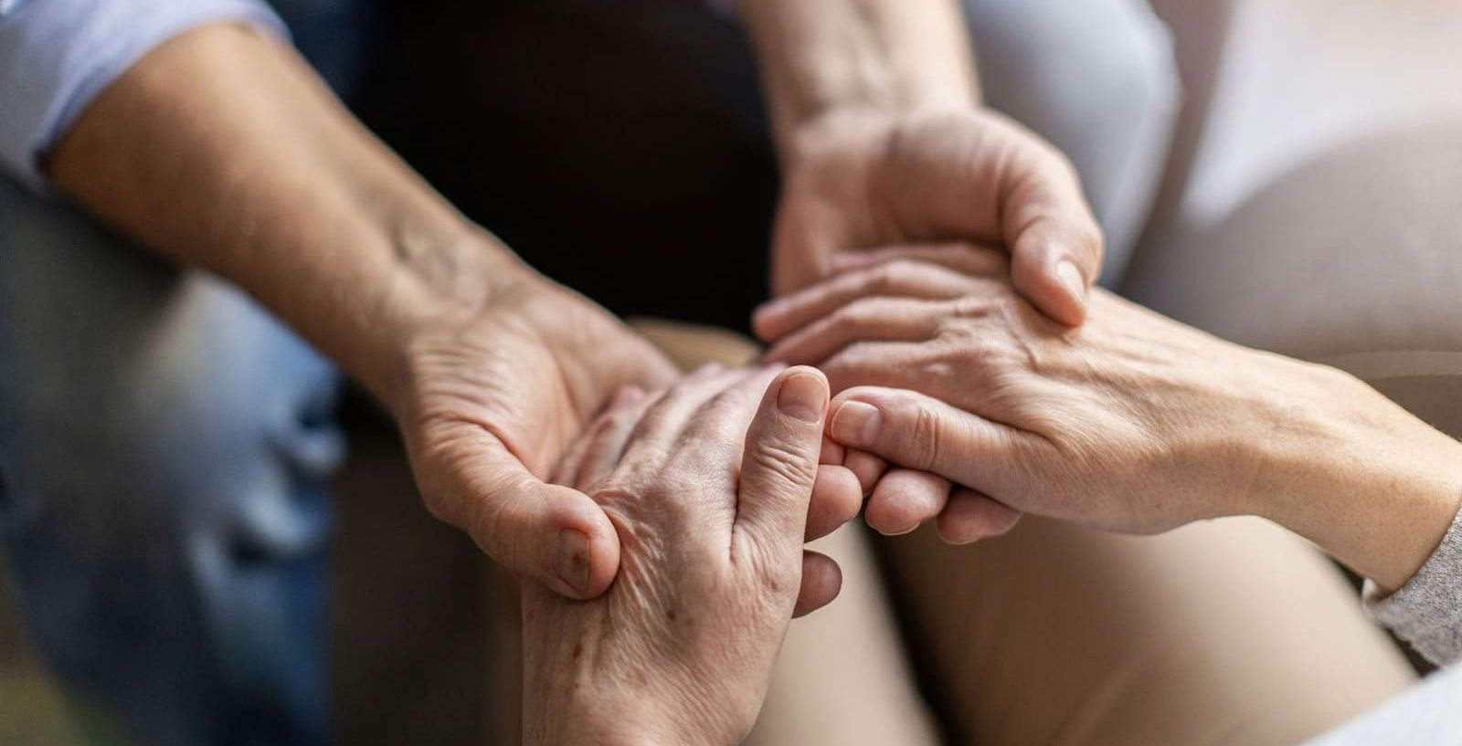 A man and a woman are holding hands while sitting on a couch.