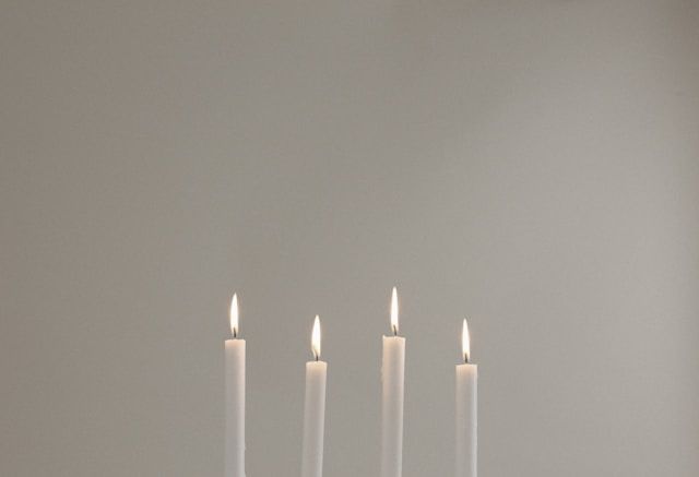 Four lit candles against neutral background, symbolizing remembrance, cremation services Santa Rosa,