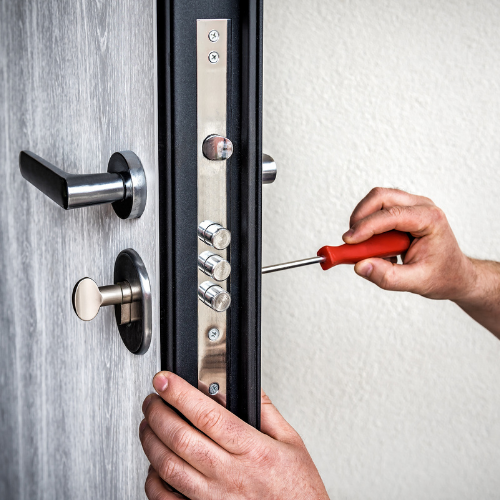 A person is fixing a security door lock with a screwdriver. Oswestry Locksmiths