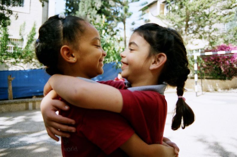 Two young girls hugging each other in a park
