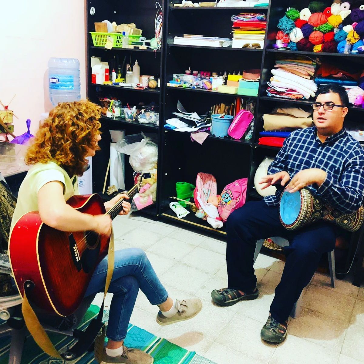 A woman is playing a guitar and a man is playing drums