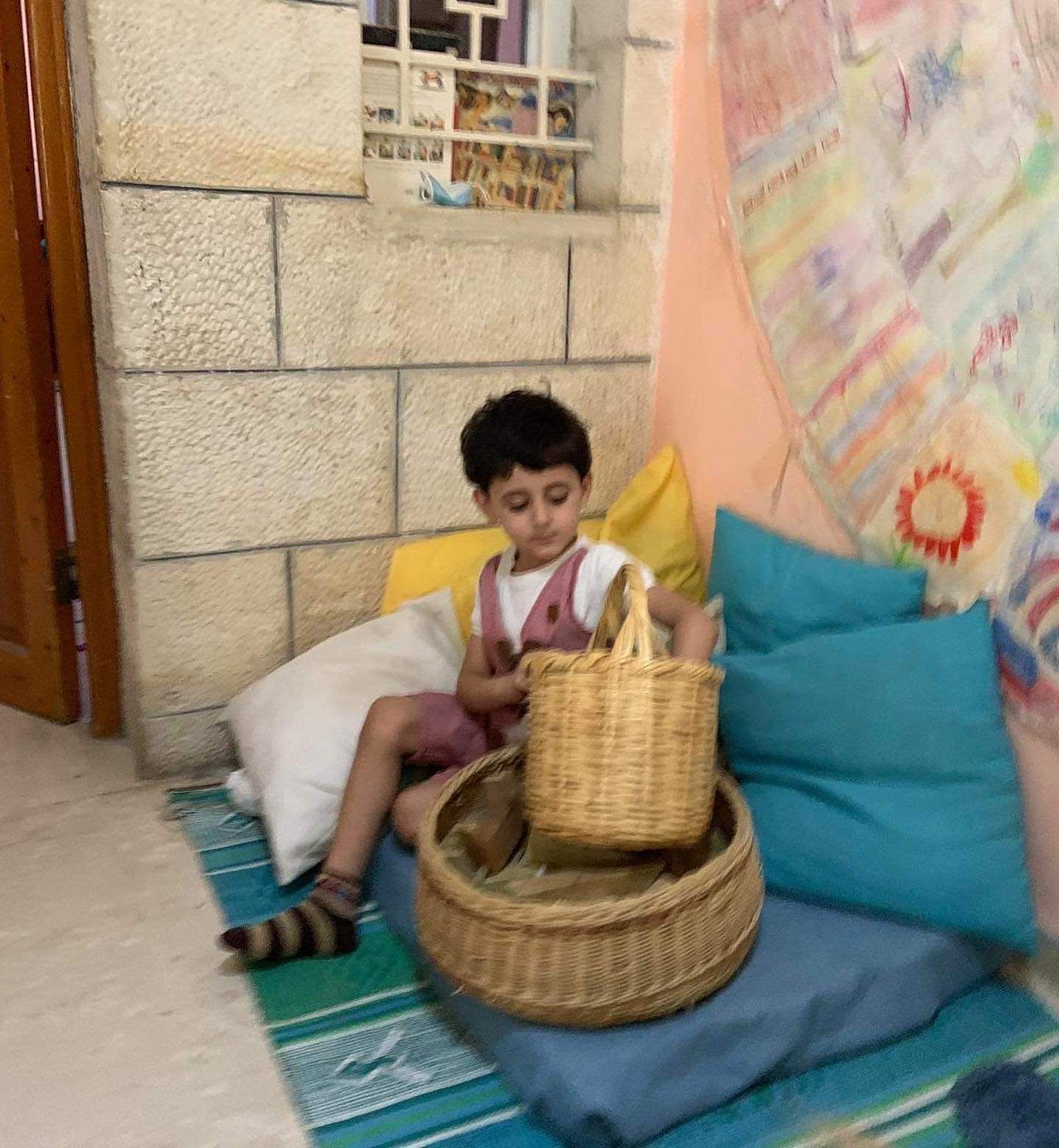 A little boy is sitting on a couch holding a basket.