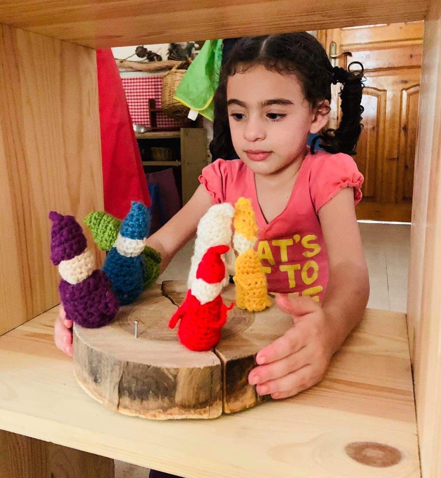 A little girl playing with puppets on a wooden puppet stage 