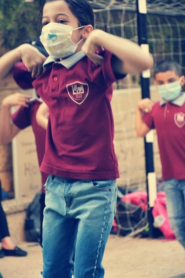 A boy wearing a mask and a maroon shirt with a shield on it