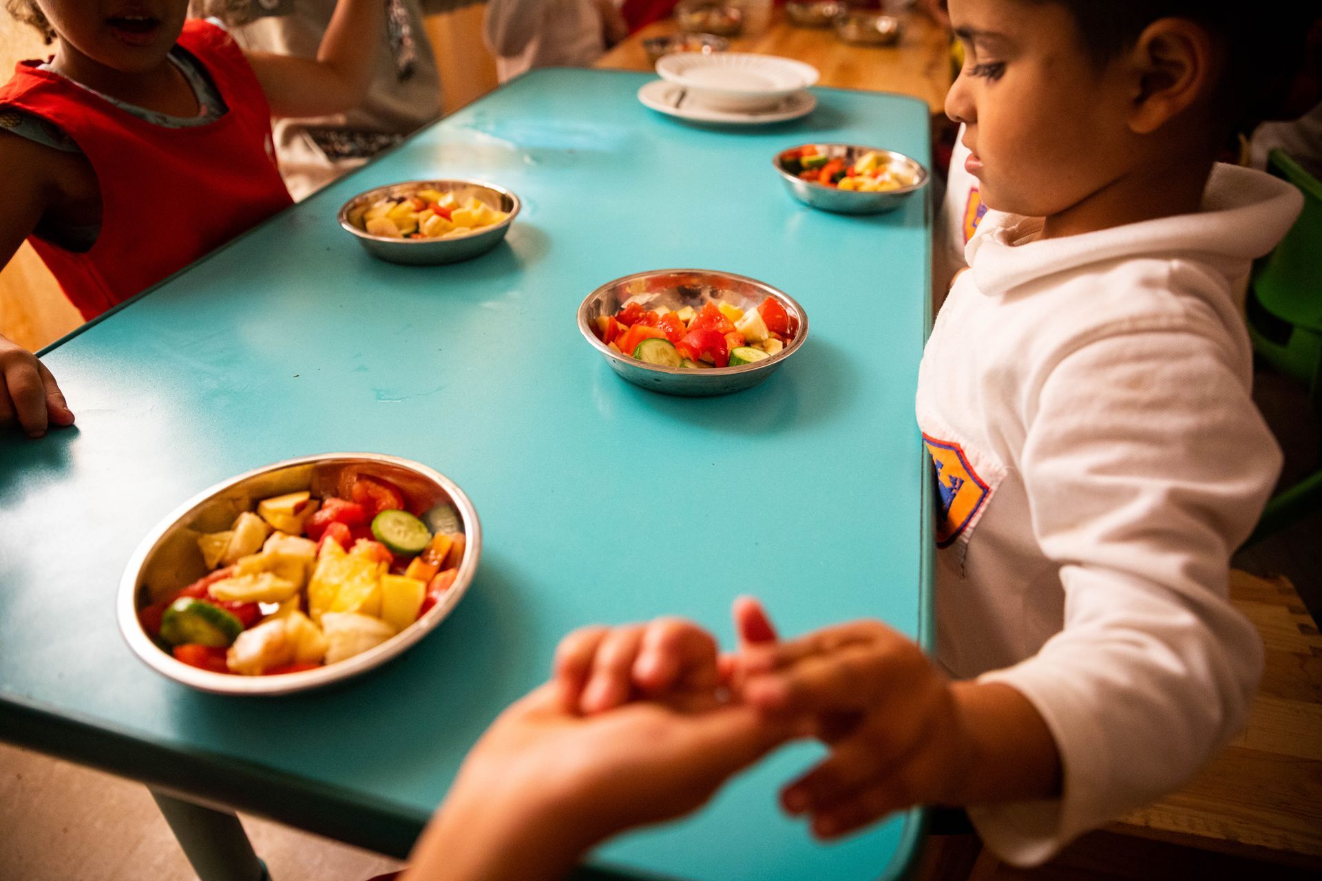 Children eating colorful fruit bowls around a turquoise table