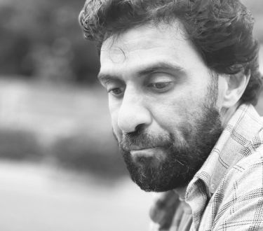 A man with a beard is looking down in a black and white photo.