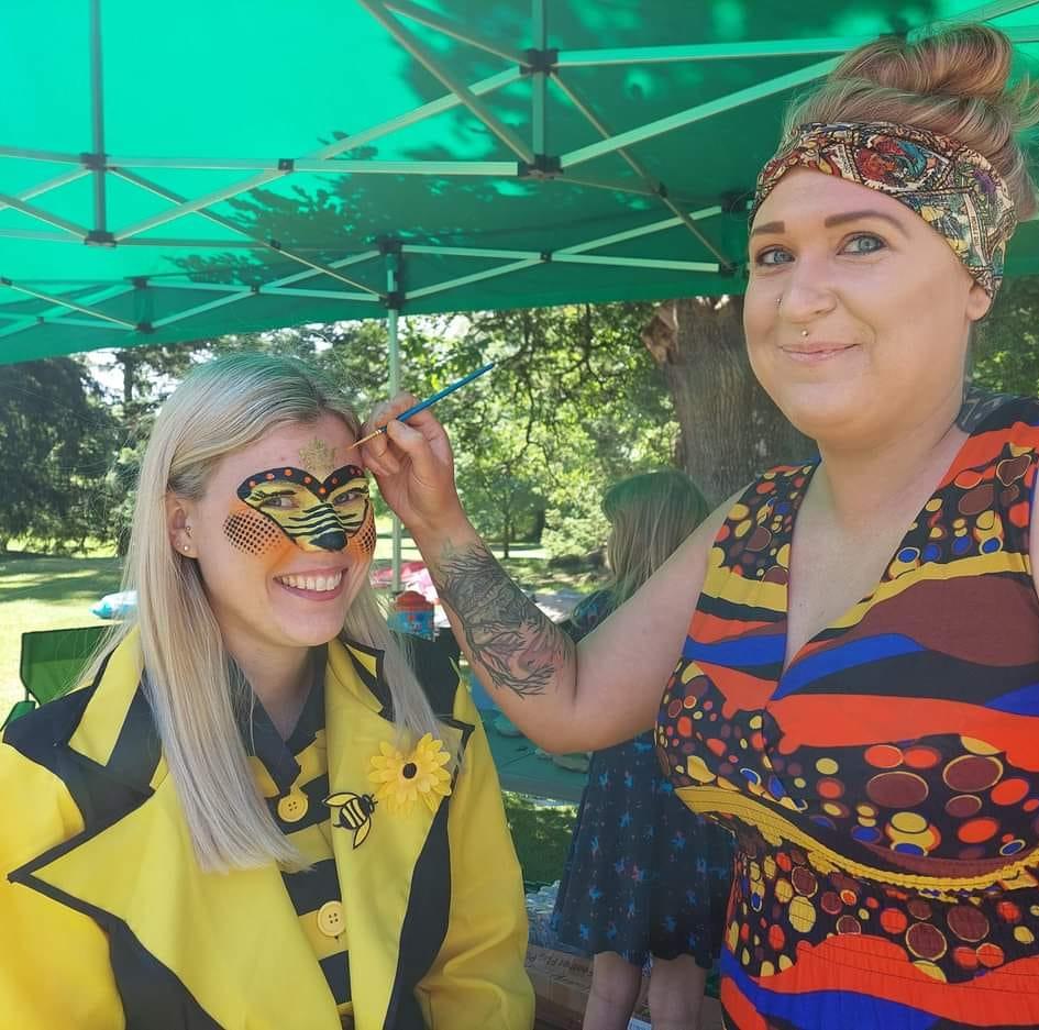 A woman is painting another woman 's face with a brush