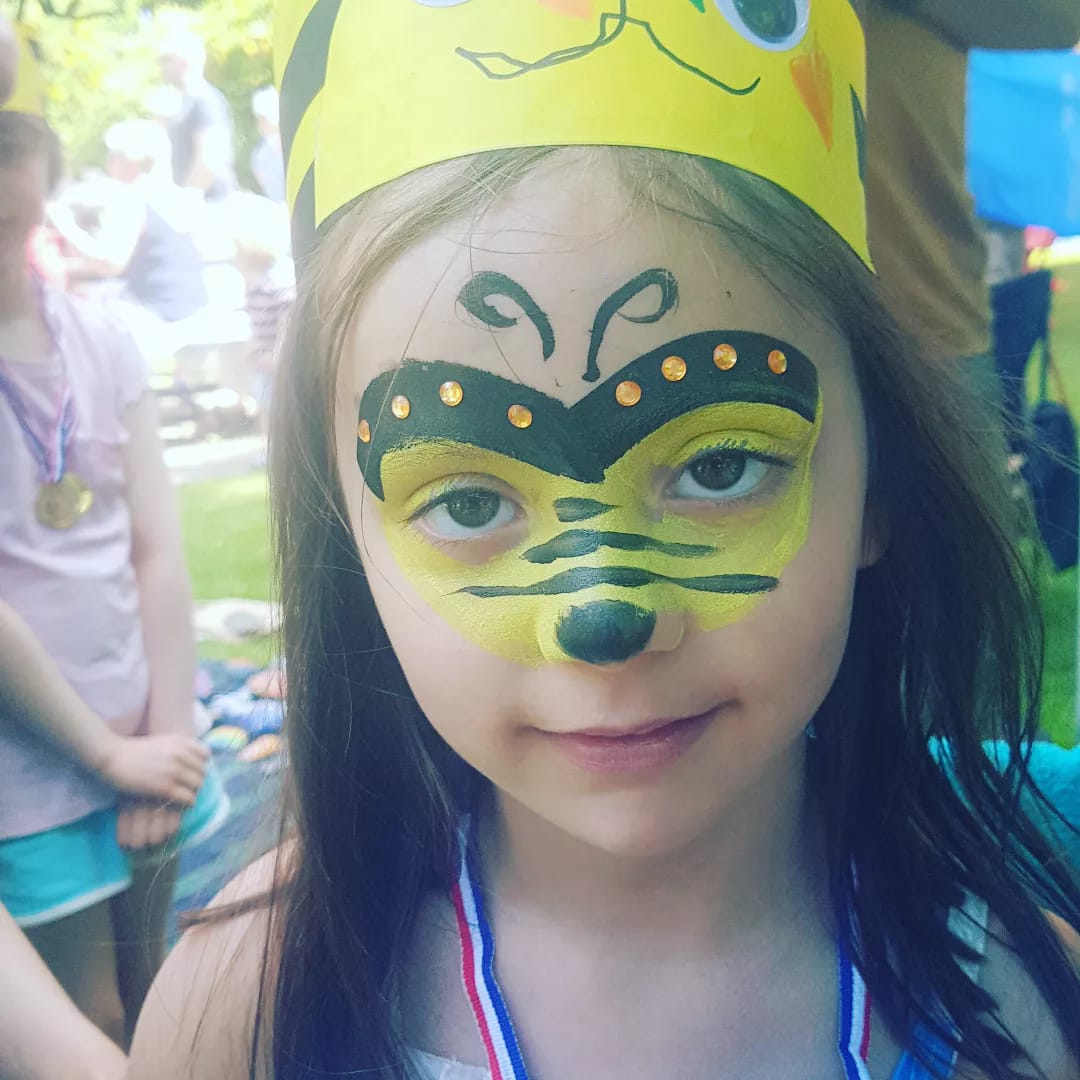 A little girl with a bee face painted on her face
