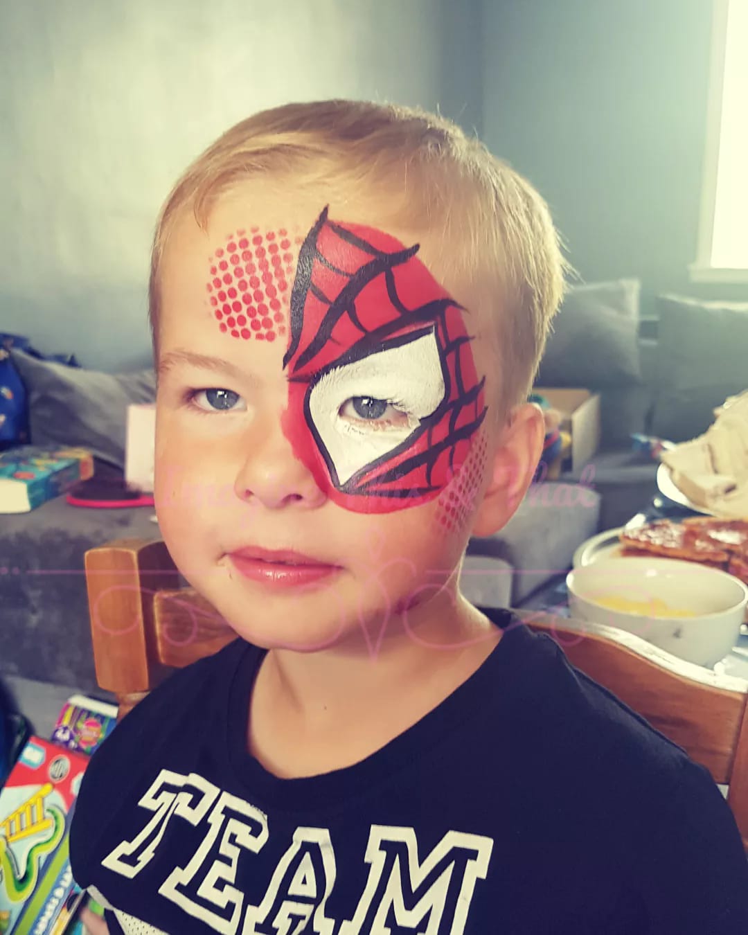 A young boy with a spiderman face painted on his face