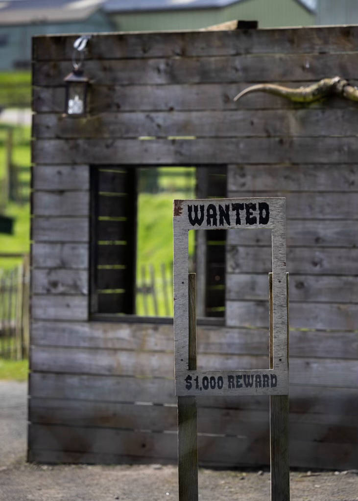 A wooden building with a wanted sign in front of it