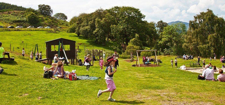 A little girl is running through a grassy field in a park.