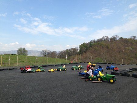 A row of toy tractors are lined up in a parking lot
