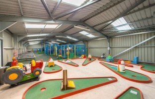 A large indoor playground with mini golf courses and a tractor.