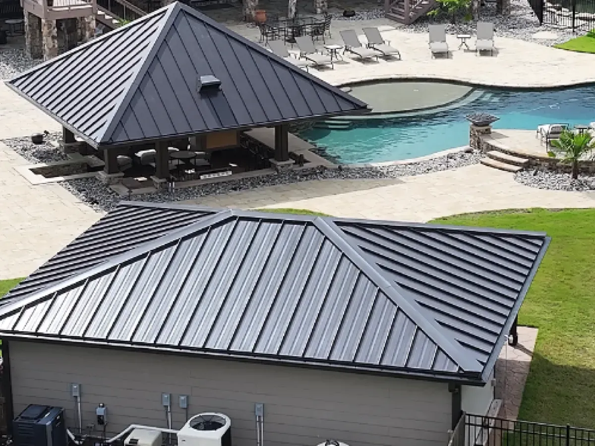 Dark gray metal roofs on a gazebo and a building near a swimming pool.