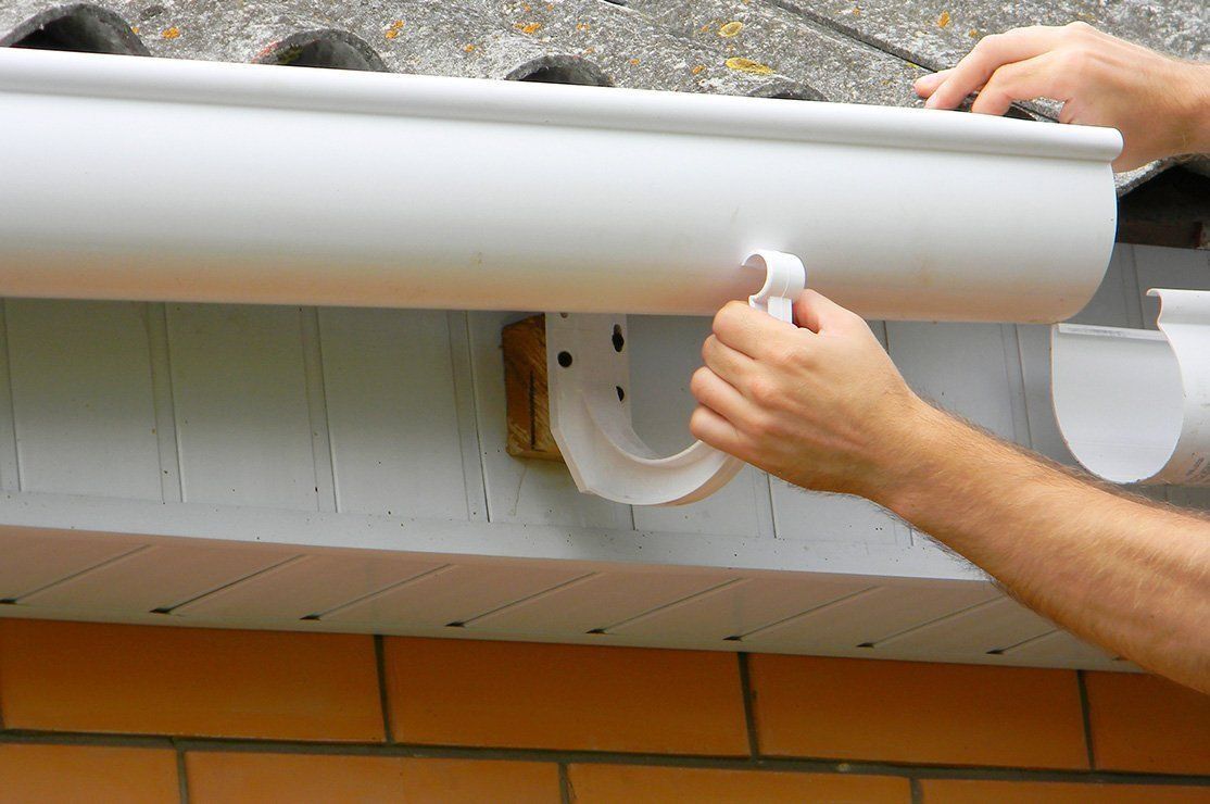 a person is installing a white gutter on a roof