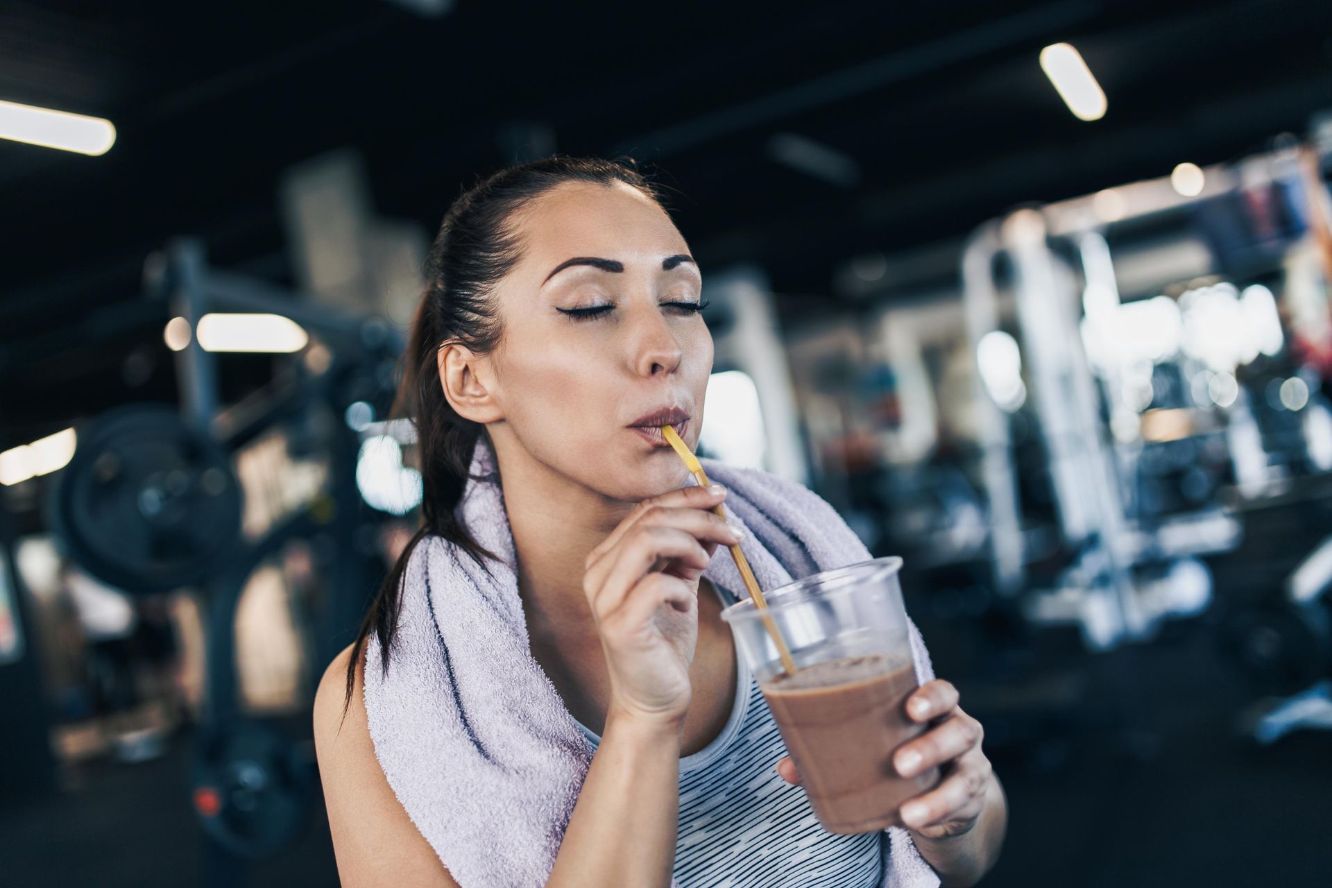Woman in gym drinks smoothie after workout.