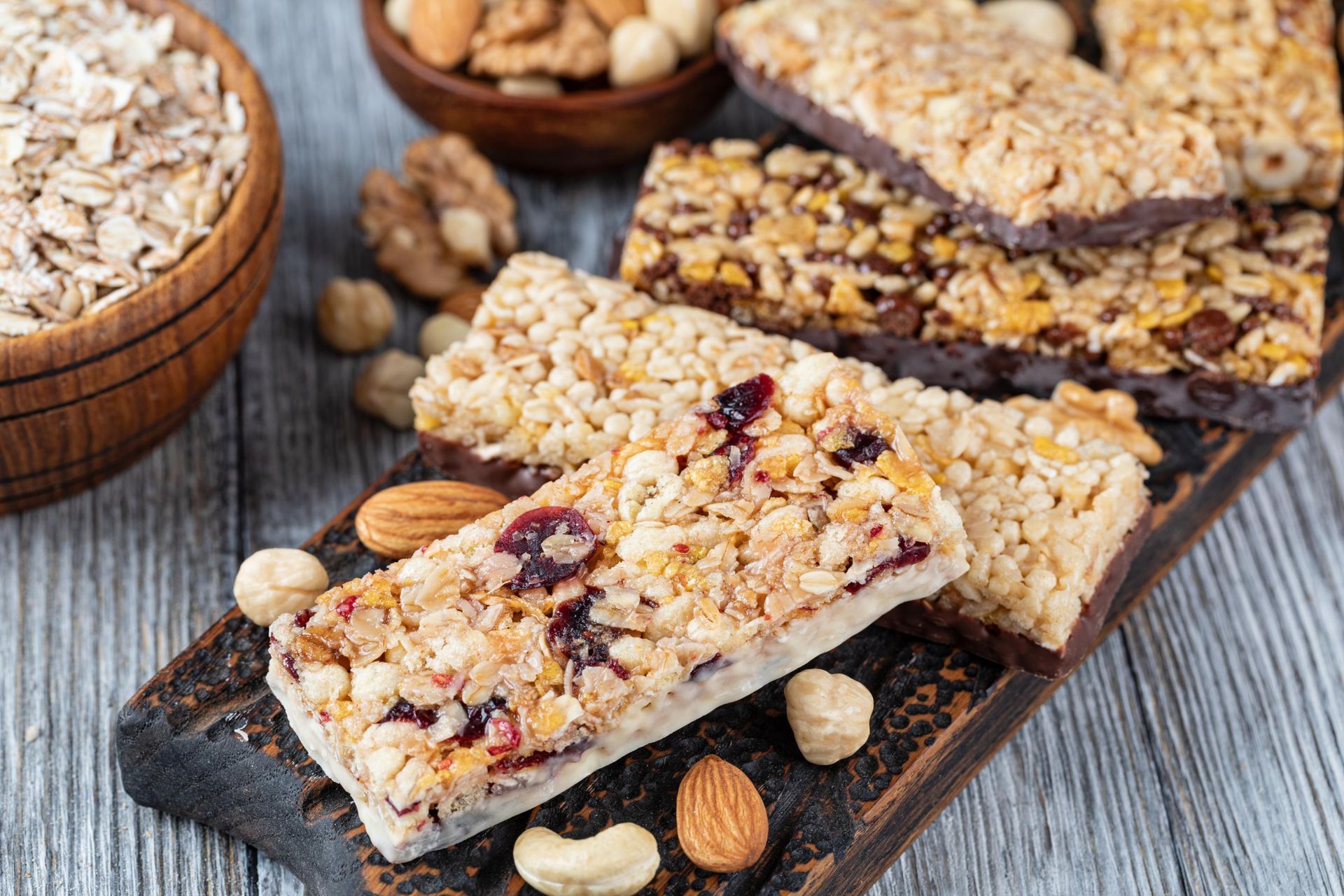 Granola bars, nuts, and oats on a wooden board.