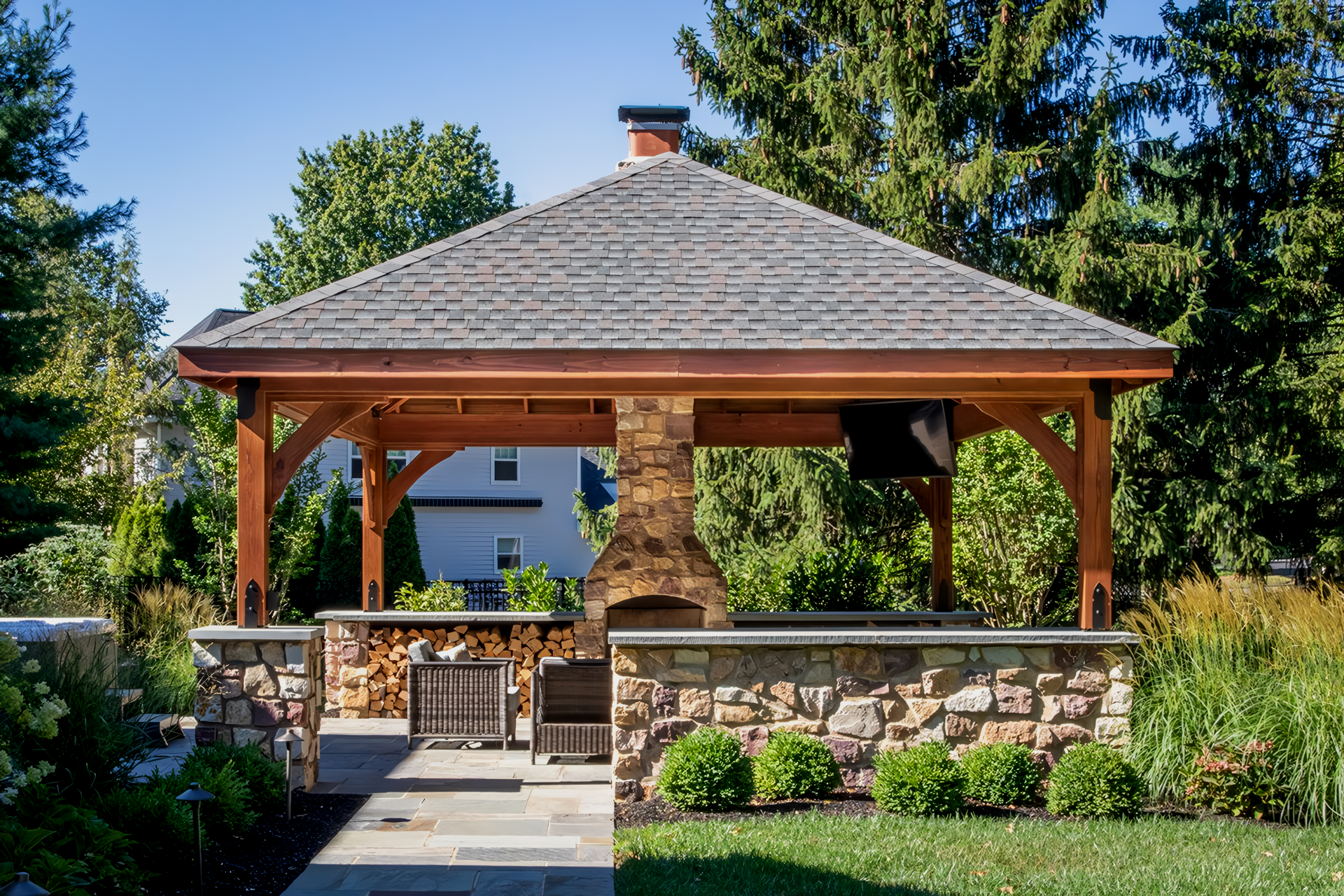 A fire pit is under a pergola in a backyard
