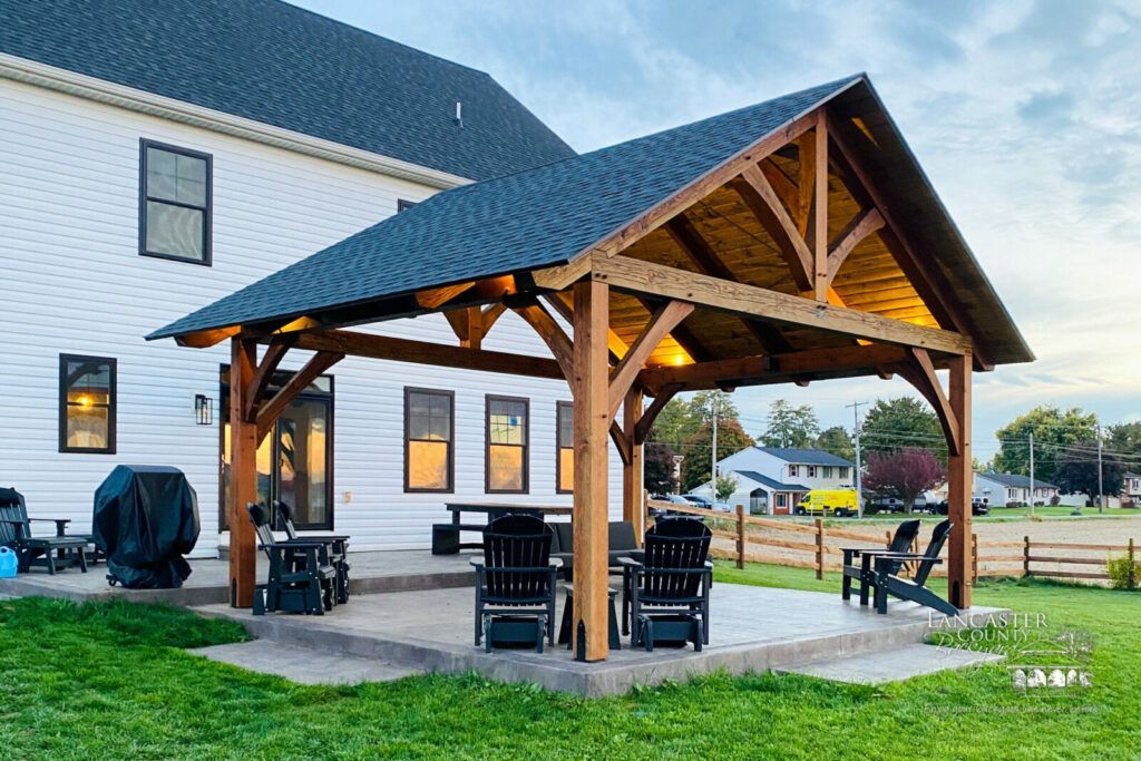 A dog is standing in front of a pavilion with a fireplace.