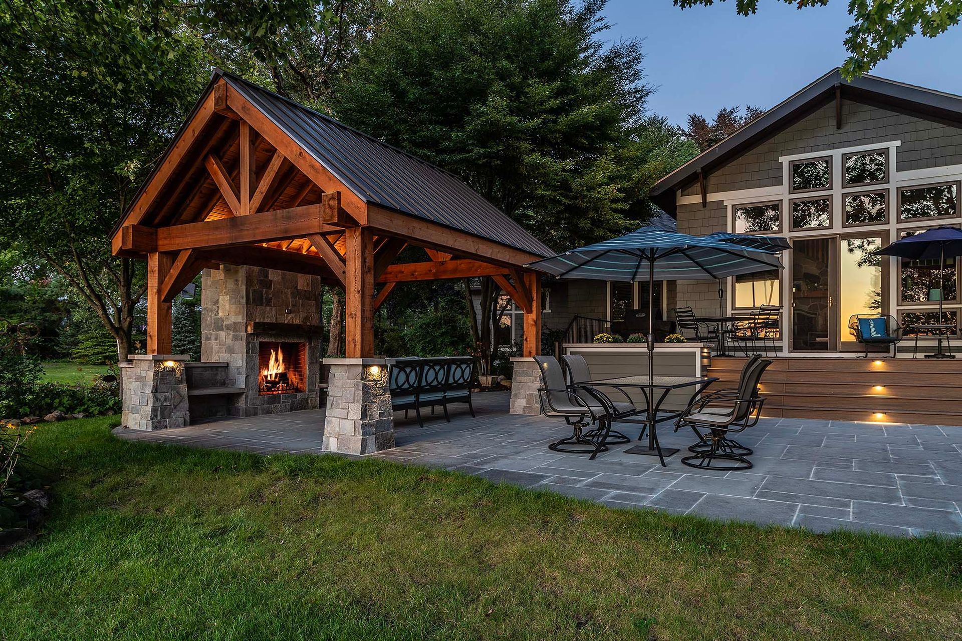 A dog is standing in front of a pavilion with a fireplace.