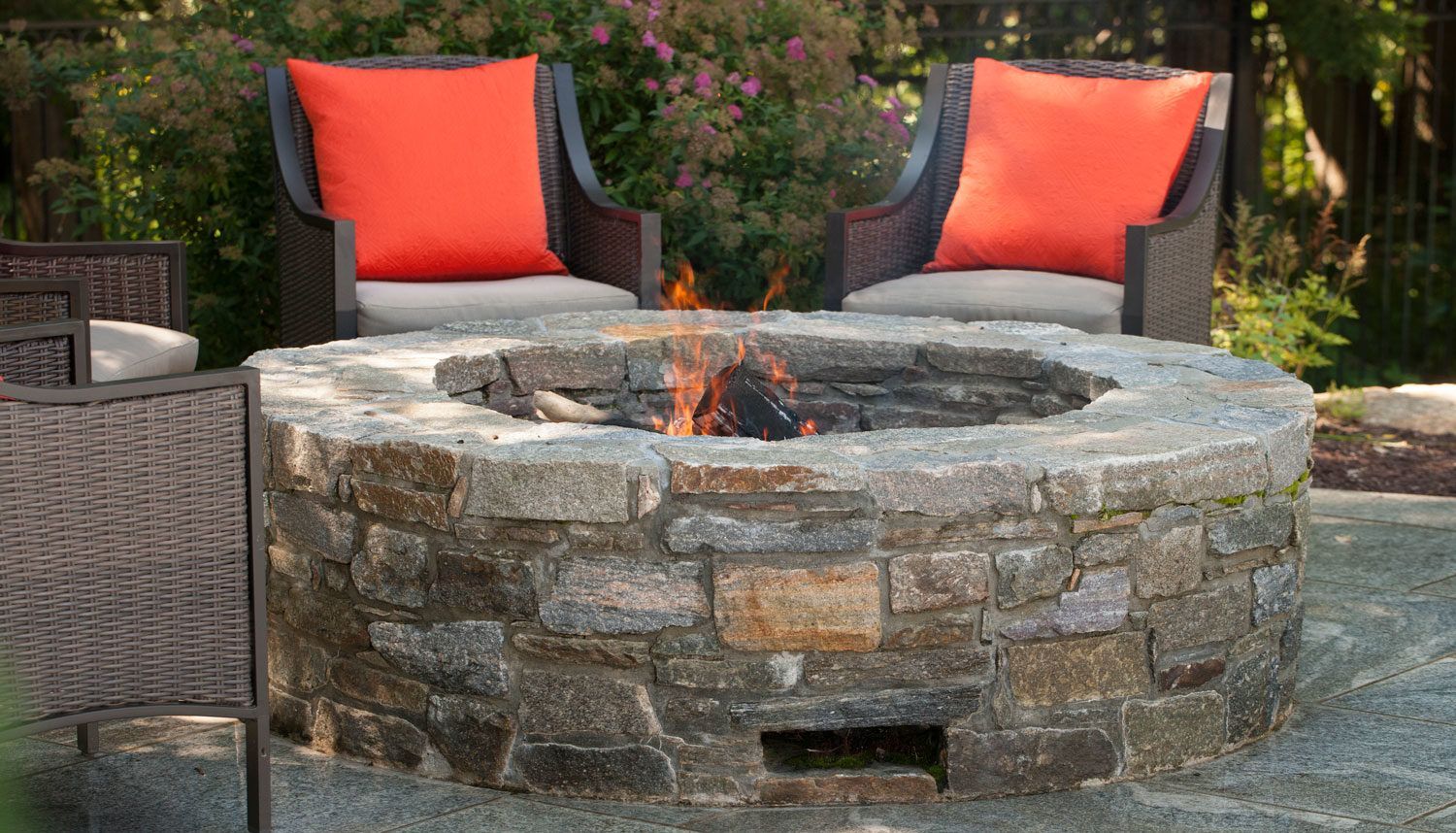 A patio with a fire pit and a couch and chair.